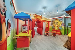 Una habitación colorida con un tiovivo, puesto de palomitas y una zona temática de Mickey Mouse.