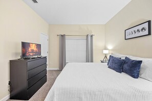 A hotel room with a bed, a dresser, a television displaying a fire, a window with curtains, and a wall-mounted picture of the moon phases. - 4BR house with private pool in Paradise Palms (Kissimmee)