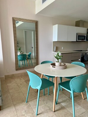 A dining area with a round table, teal chairs, and a large mirror on the wall. - Buenaventura Luxury Condo Beach Club • Golf (Río Hato)