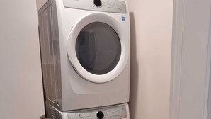 Een gestapelde wasmachine en droger in een gang.