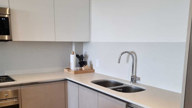 Een moderne keuken met roestvrijstalen apparatuur, een dubbele spoelbak en lichtkleurige kastjes.