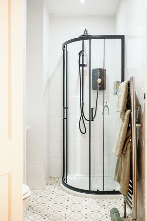 Een moderne badkamer met een douchecabine van glas, witte betegelde muren en vloertegels met een patroon.