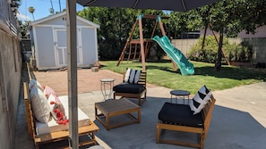 A patio area with outdoor furniture, a swing set, and a slide. - Charming 3-bedroom house centrally located in Los Angeles with AC (Los Angeles)