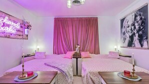 A pink-themed bedroom with two beds, a neon sign, and a large portrait on the wall. - Music Row | 5 Legend-Themed Suites | Sleeps 26 (Nashville)