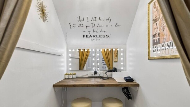 A vanity area with a mirror, lights, and a quote on the wall. - Music Row | 5 Legend-Themed Suites | Sleeps 26 (Nashville)
