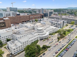 A multi-story building with a curved central section, surrounded by parking lots and roads. - Music Row | 5 Legend-Themed Suites | Sleeps 26 (Nashville)