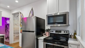 A modern kitchen with stainless steel appliances, a microwave, and an oven. - Music Row | 5 Legend-Themed Suites | Sleeps 26 (Nashville)