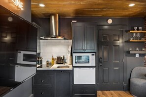 A modern kitchen with dark cabinetry, stainless steel appliances, and a wooden ceiling. - Music Row | 5 Legend-Themed Suites | Sleeps 26 (Nashville)