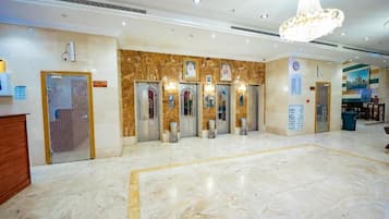 Vestíbulo de hotel con suelo de mármol, candelabro y mostrador de recepción.