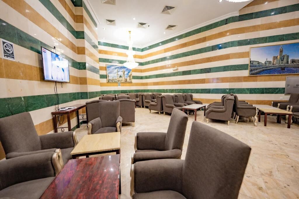 Um saguão de hotel com paredes listradas, várias áreas de estar, uma televisão e uma pintura com vista para a cidade.