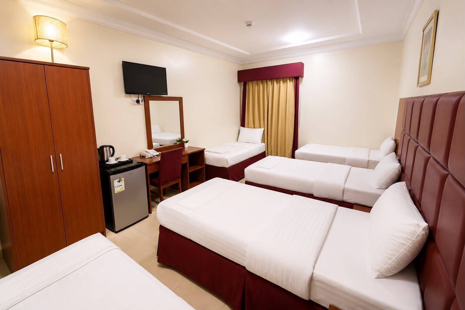Habitación de hotel con dos camas, un escritorio, televisor, minibar y armario.
