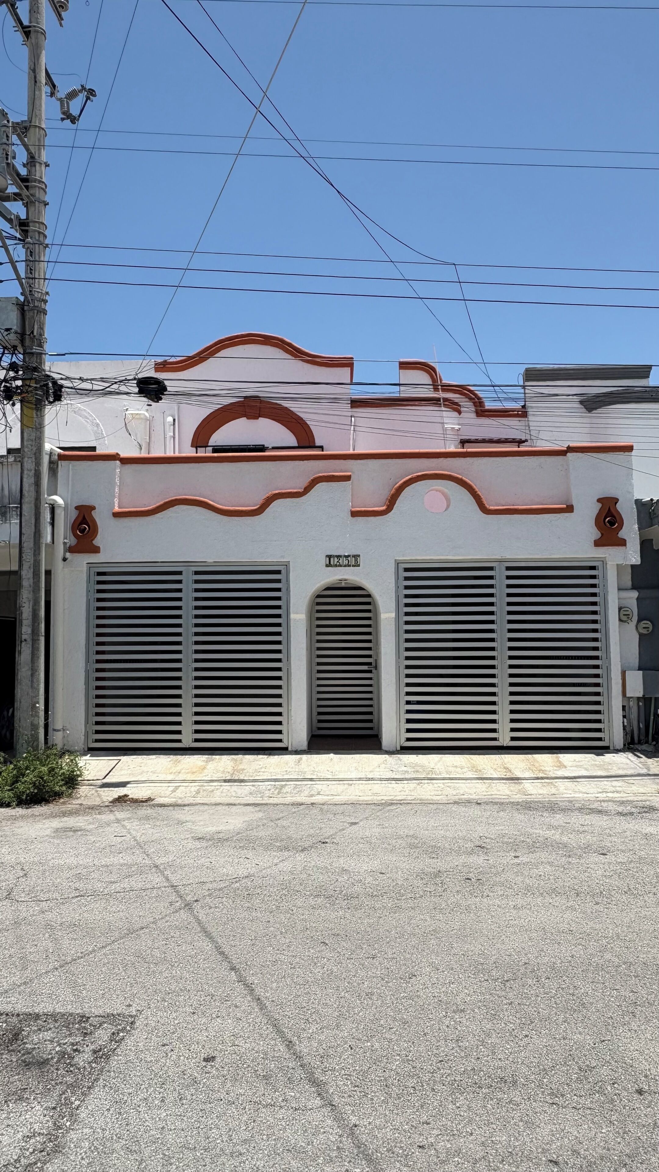 Un bâtiment doté d’une grande porte de garage, d’une petite entrée en arc de cercle et d’une enseigne au-dessus de la porte.