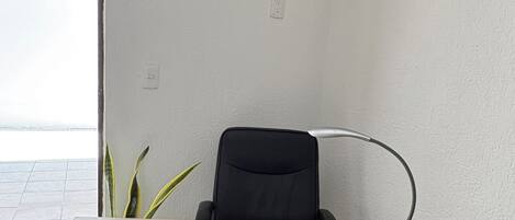 A corner office with a desk, chair, and a desk lamp.