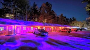 A motel with a row of rooms, a parking lot, and a forested area in the background. - Charming Studio 15, Pets Welcome, Near Dollywood, Near The Strip (Pigeon Forge)