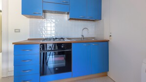 Eine Küche mit blauen Schränken, einer Edelstahl-Spüle und einem eingebauten Backofen.