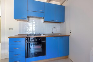 A kitchen with blue cabinets, a stainless steel sink, and a built-in oven. - Ca` Mele by BarbarHouse (Lecce)