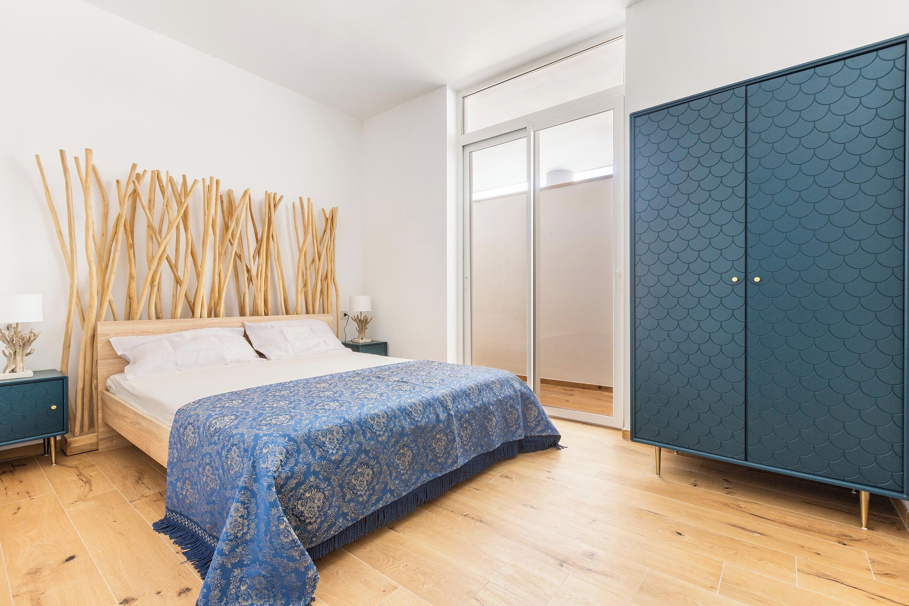 A bedroom with a bed, a wardrobe, and a nightstand.