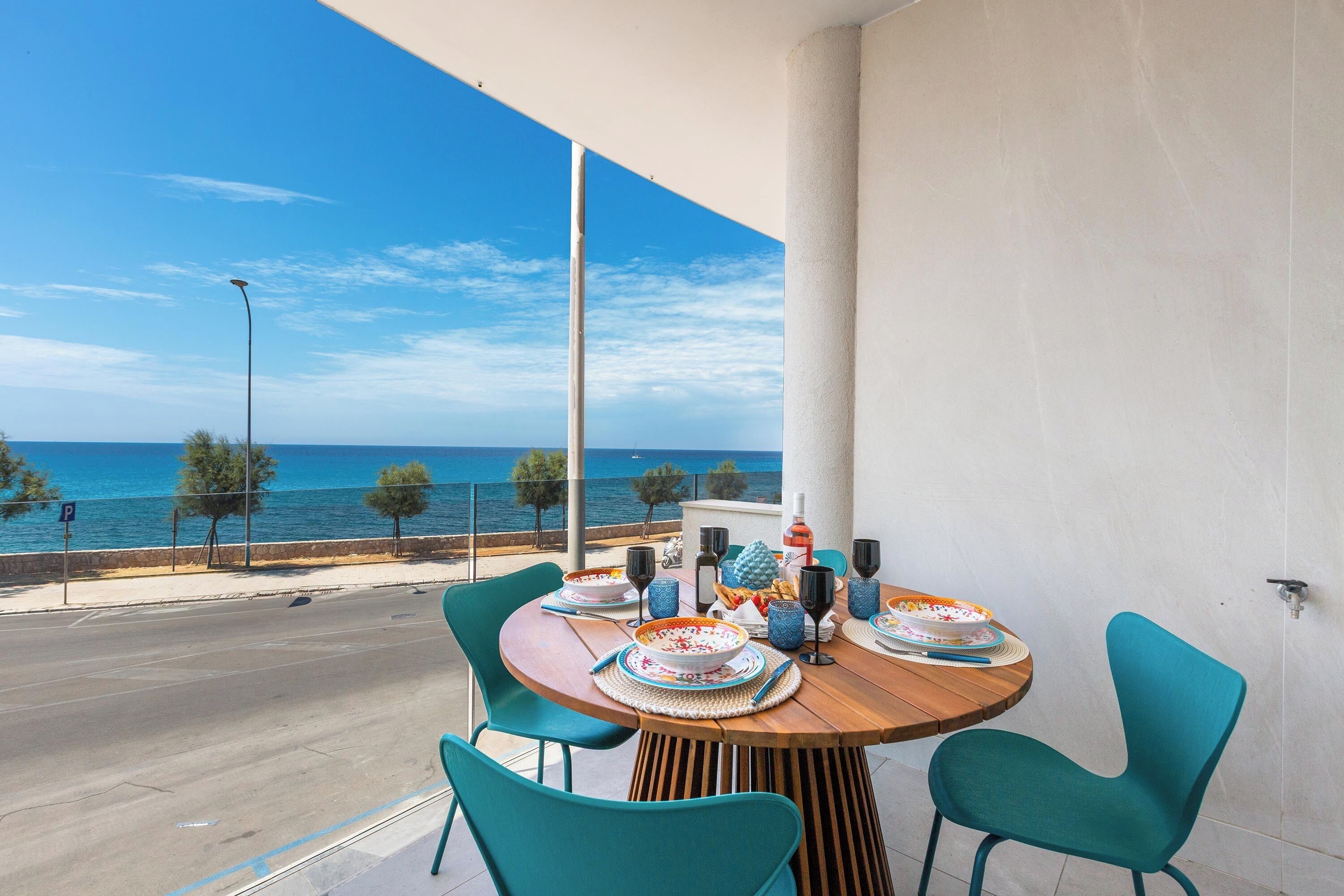 Ein Balkon mit Esstisch, der Blick auf die Küste freigibt.