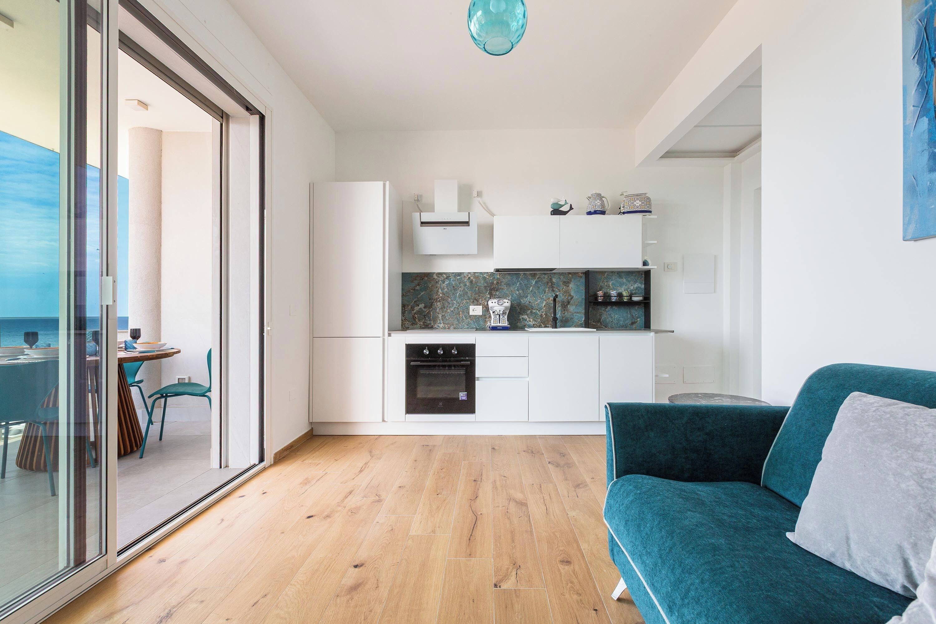 Een moderne keuken met witte kastjes, een inbouwoven en een aanrecht met decoratieve objecten.