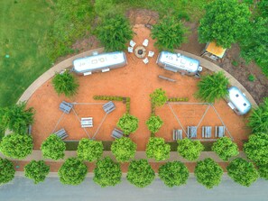 Vue aérienne d’un terrain de camping avec des camping-cars, des tables de pique-nique et des arbres.