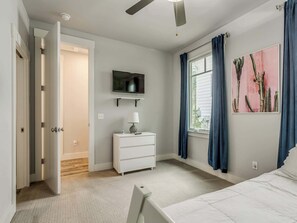 A bedroom with a bed, a dresser, a television, and a window with curtains. - Peace of Mind - Pet Friendly Luxury Getaway in Carlton Landing (Eufaula)