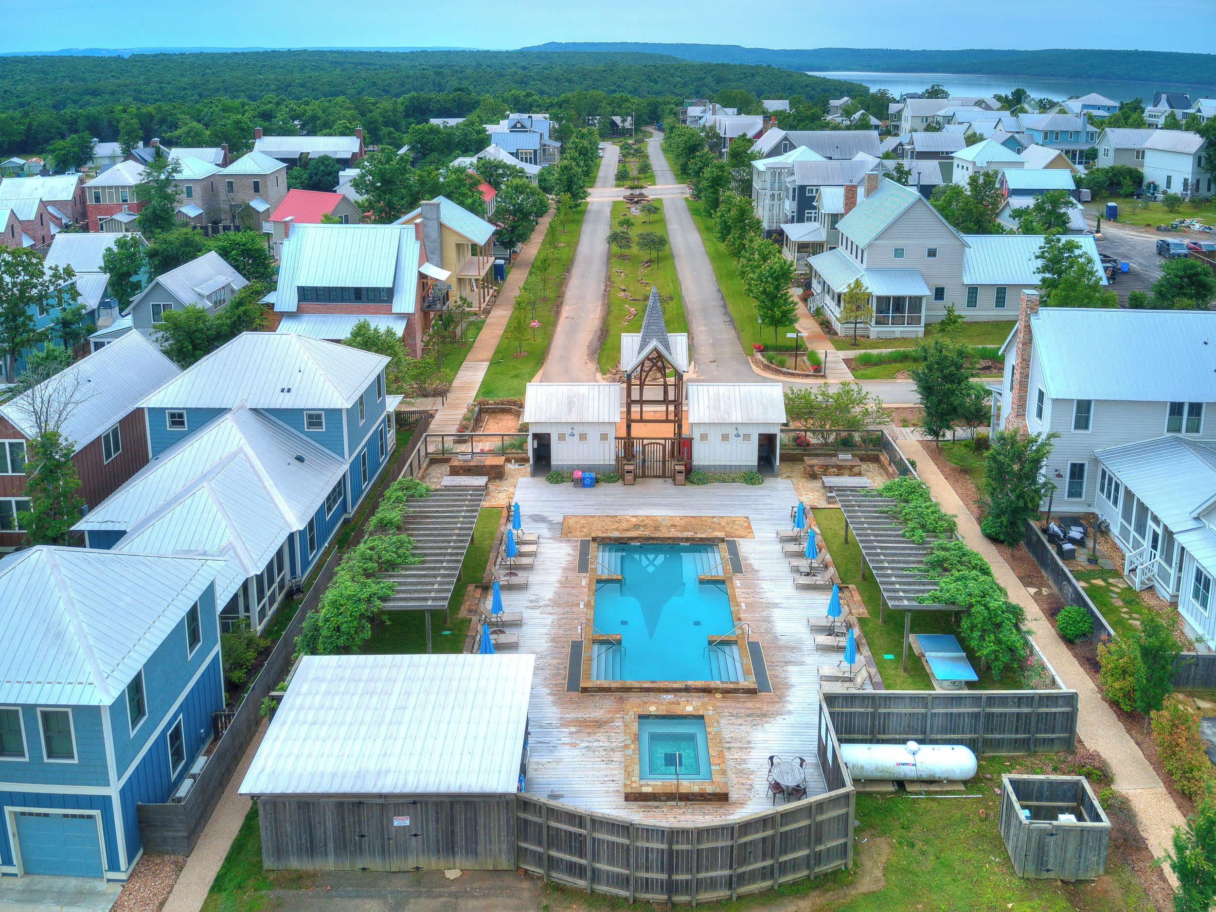 A residential area with houses, a central pool, and a view of the water body in the distance.