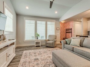 A spacious living room with a large window, a sofa, a chair, and a small table with a plant. - Peace of Mind - Pet Friendly Luxury Getaway in Carlton Landing (Eufaula)