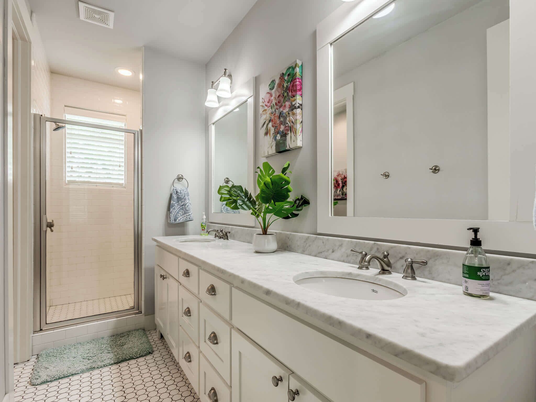 A bathroom with a large mirror, a sink, and a shower.