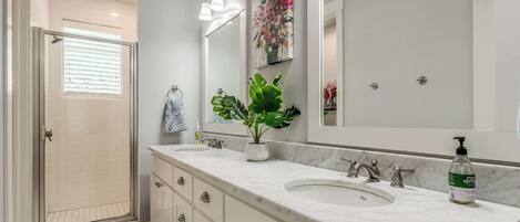 A bathroom with a large mirror, a sink, and a shower.