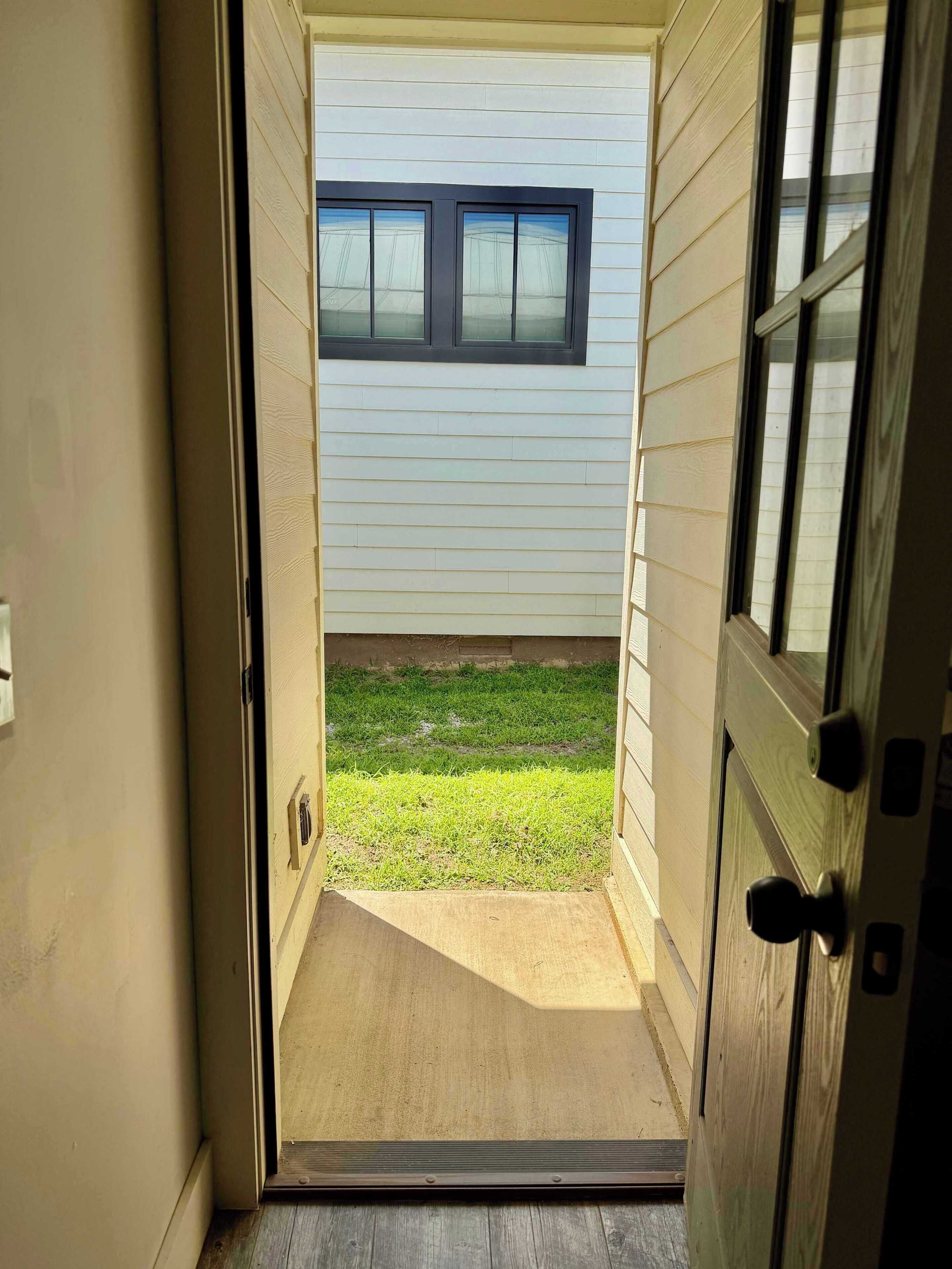An open door leading to a covered porch with a window above it.