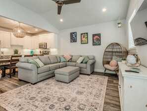 A modern living room with a sectional sofa, a round chair, a globe on a cabinet, and a kitchen in the background. - Peace of Mind - Pet Friendly Luxury Getaway in Carlton Landing (Eufaula)