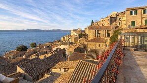 A coastal town with stone buildings, terracotta roofs, and a view of the sea. - Charming 2-Bedroom Home | Terrace & Great Lake View (Anguillara Sabazia)