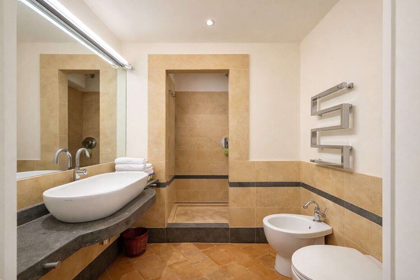 A modern bathroom with a large sink, a toilet, and a bidet.