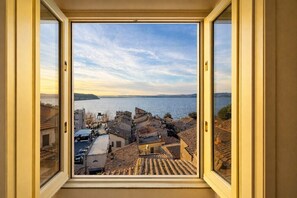 A view from a window overlooking a coastal town with buildings and a body of water.