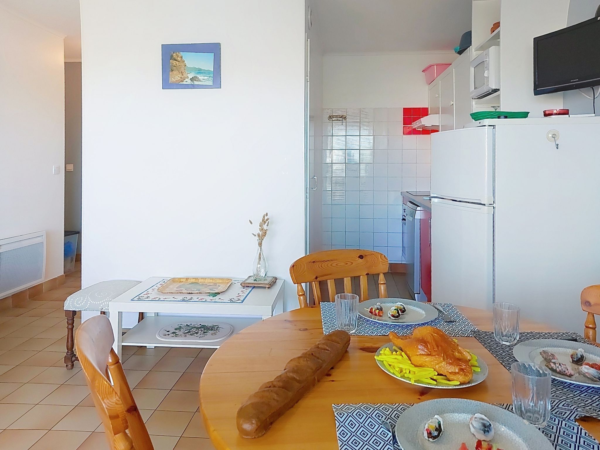 Un comedor con una mesa de madera, sillas y vista a la cocina.