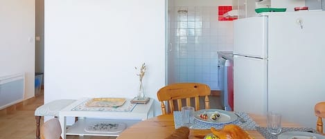 Un comedor con una mesa de madera, sillas y vista a la cocina.