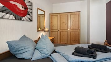 A bedroom with a bed, pillows, a mirror, a wardrobe, and a wall art piece.