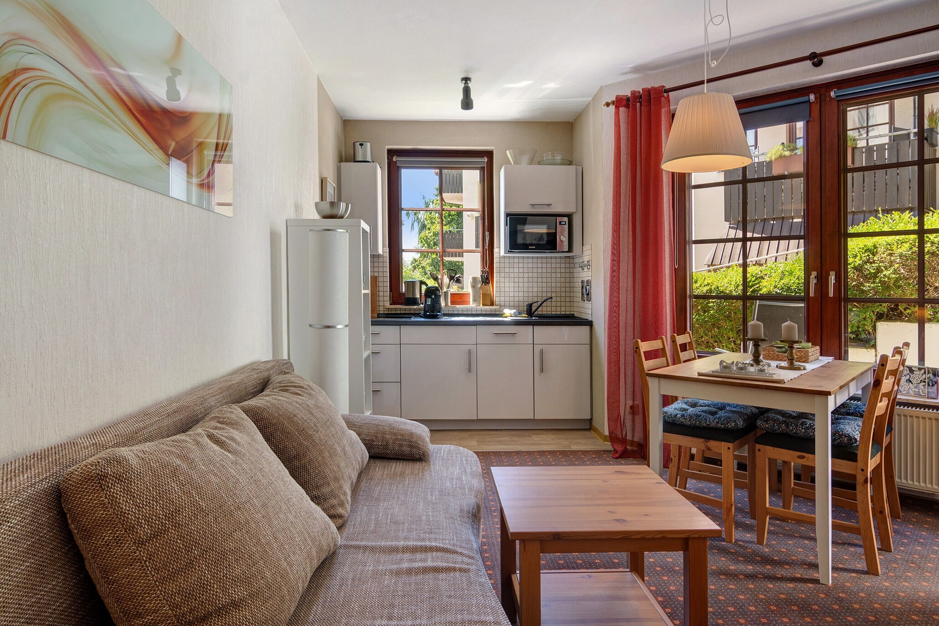 A compact living space with a kitchenette, a dining area with a table and chairs, and a sofa.