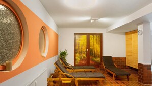 A room with two wooden lounge chairs, a large window with a view of a forest, and a wooden cabinet with a clock. - Apartment 'Harzidyll' with Wi-Fi (Bad Sachsa)