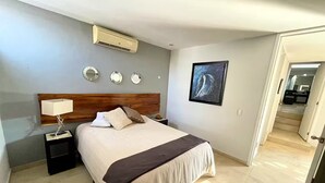 A hotel room with a bed, bedside tables, a wall-mounted air conditioner, and a framed artwork. - Piece Of Paradise In The City (Guadalajara)