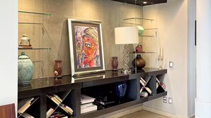 A modern interior with a built-in console table displaying books and decorative items, a framed painting, and a wall-mounted lamp. - Piece Of Paradise In The City (Guadalajara)