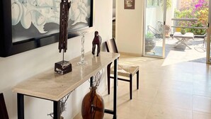 A spacious room with a large painting, a dining table, chairs, and a view through a glass door to an outdoor area with plants and a patio. - Piece Of Paradise In The City (Guadalajara)