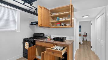 Una cocina compacta con estufa a gas, armarios de madera y encimera con escurreplatos.