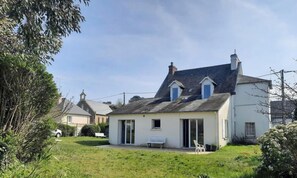 Une maison à deux étages avec un toit en pente, un petit porche et un banc.