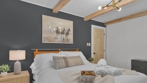 Ein Schlafzimmer mit Bett, Nachttisch, Lampe und einem Bild an der Wand.