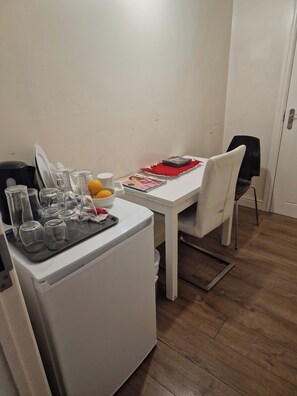 Eine kompakte Küche mit Kühlschrank, einem Esstisch mit Stühlen sowie verschiedenen Küchengeräten und Utensilien.