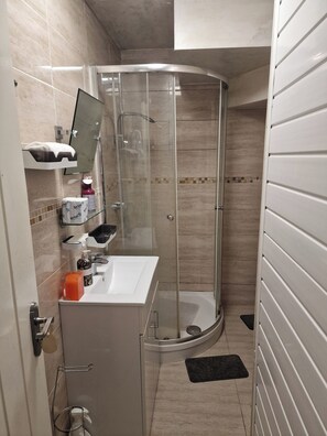 Ein modernes Badezimmer mit Duschkabine aus Glas, einem weißen Waschbecken und einem Spiegel.