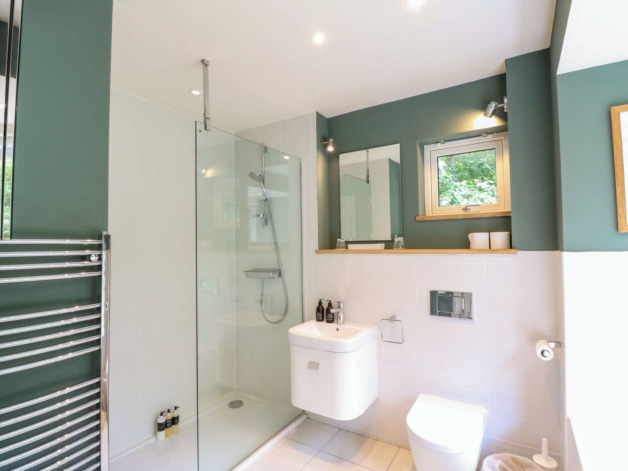 A modern bathroom with a glass-enclosed shower, a white sink, and a toilet.