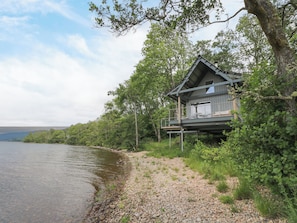 A lakeside cabin with a deck and outdoor seating area.