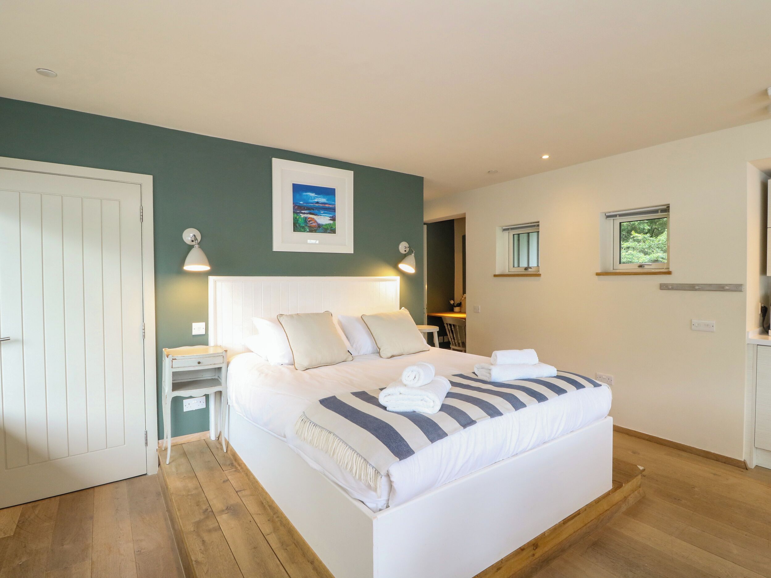 A bedroom with a bed, bedside tables, a nightstand, a framed picture, and a window.